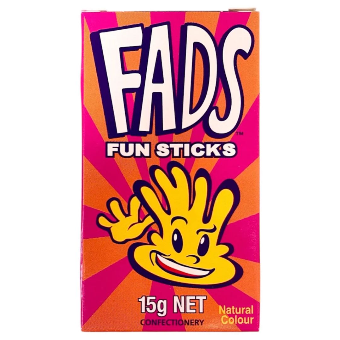 A box of FADS Fun Sticks confectionery, featuring a bright pink and orange sunburst design with the brand name 'FADS' in large white letters and a yellow cartoon character on the front.