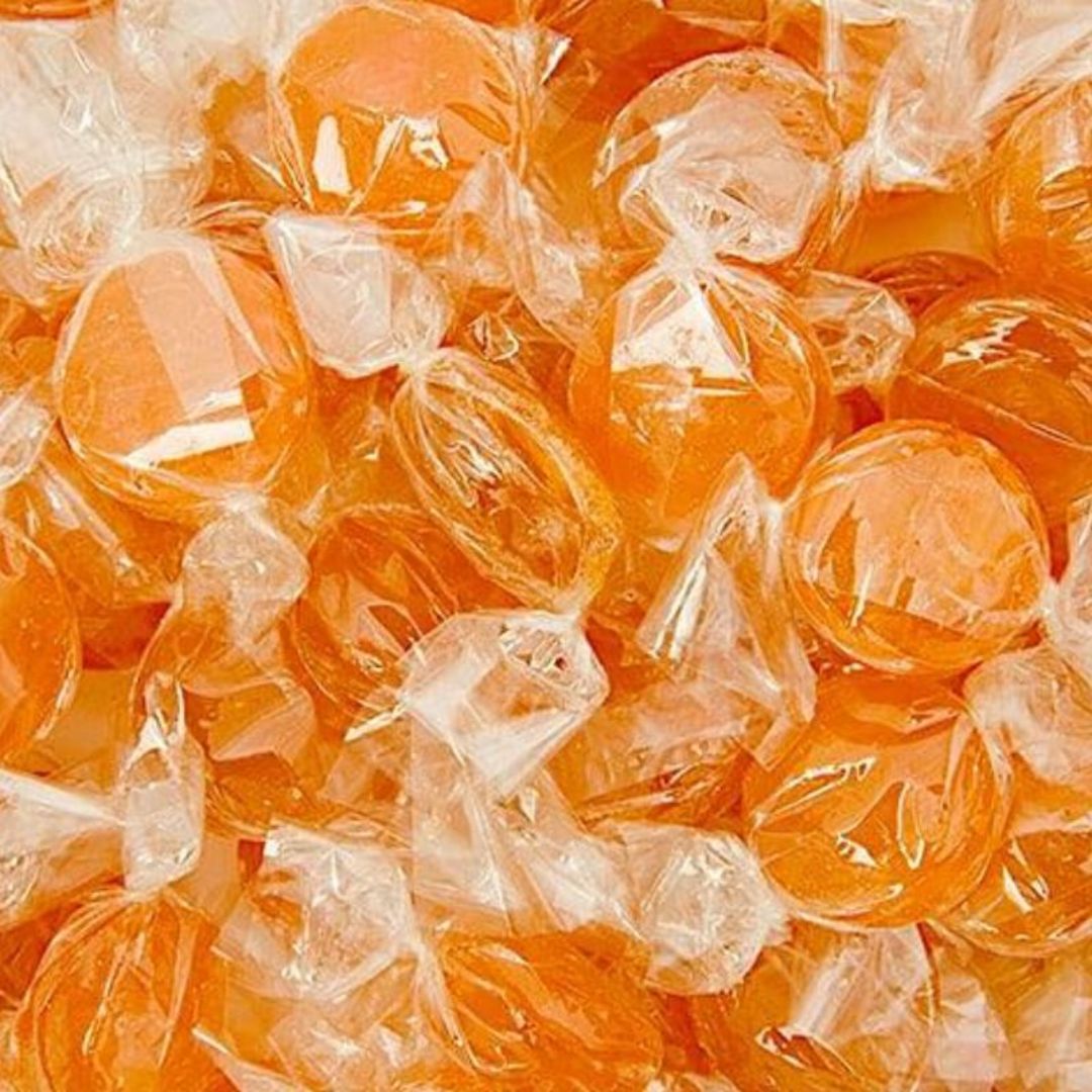 Orange hard boiled lollies wrapped in clear cellophane. 