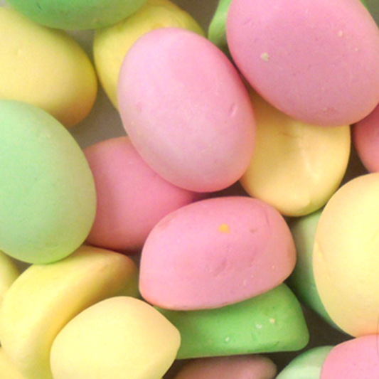 A close-up of colorful fondant treats, which are fruit puffs, in pastel green, white, and pink colors.