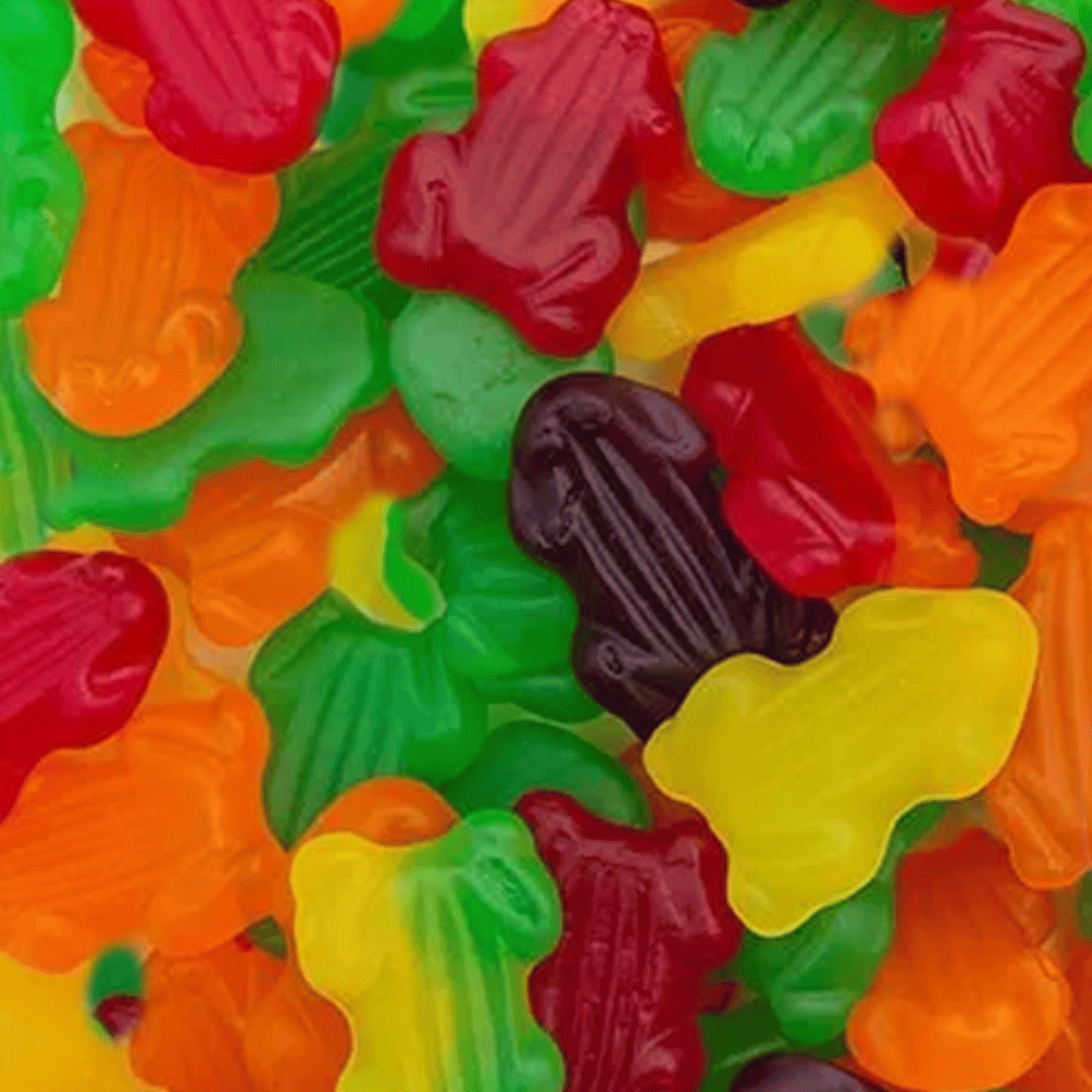 Assorted colorful gummy frogs on a textured surface