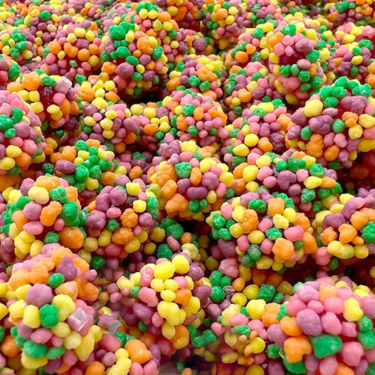A close-up image of colorful Nerds Rainbow Gummy Clusters candy, showing the chewy gummy clusters in a variety of colors including yellow, pink, green, and orange.
