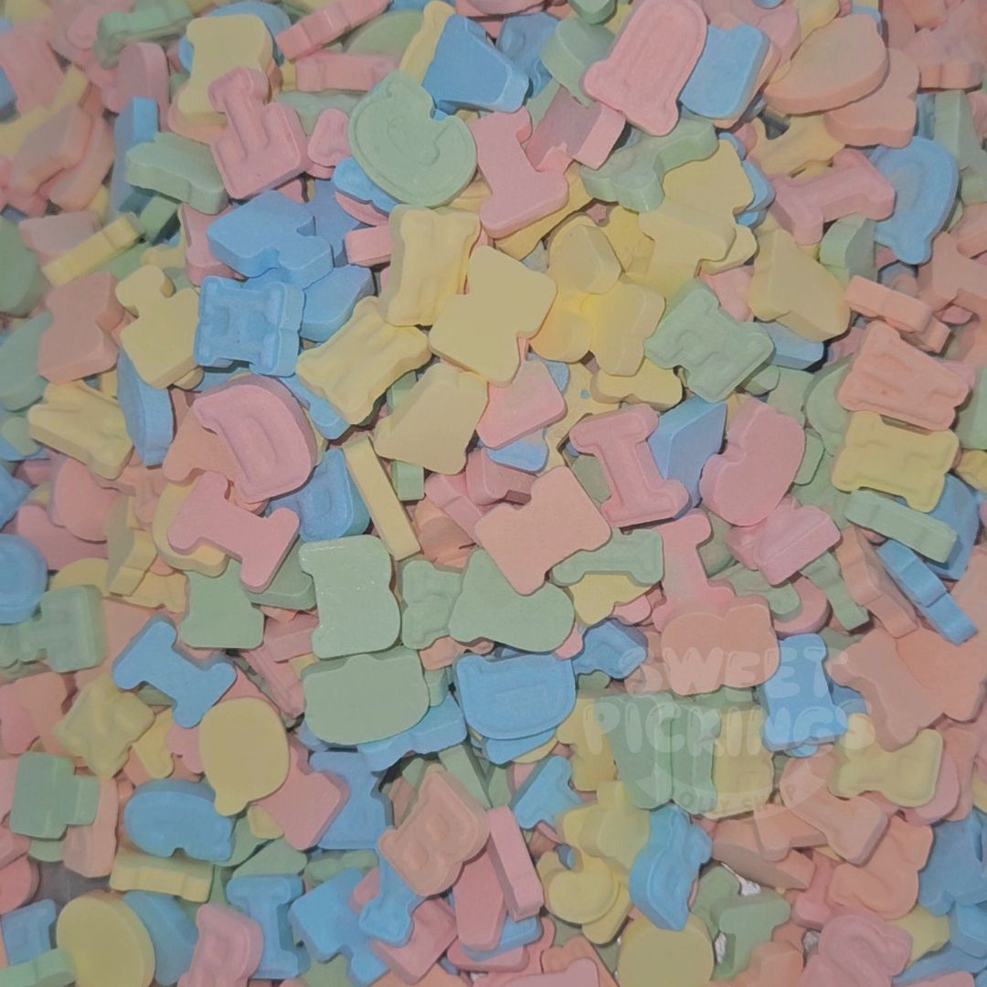 A close-up pile of pastel candy letters and shapes in pink, blue, yellow, and mint green.