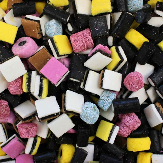 A close-up pile of assorted colorful candy pieces, including black-and-white striped pieces, pink pieces, yellow-and-black pieces, and light blue sprinkled pieces.
