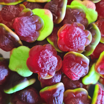 Close-up of gummy candies shaped like strawberry flowers with red and green colors.