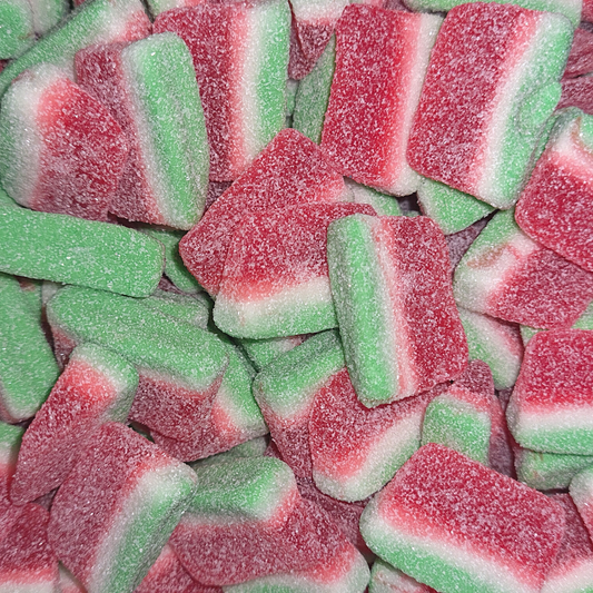 A close-up image of sugar-coated watermelon slice gummy candies, predominantly red and green in color.